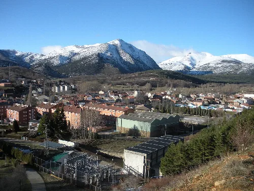Landscape of Velilla del Río Carrión with snow-capped mountains and town in the foreground.