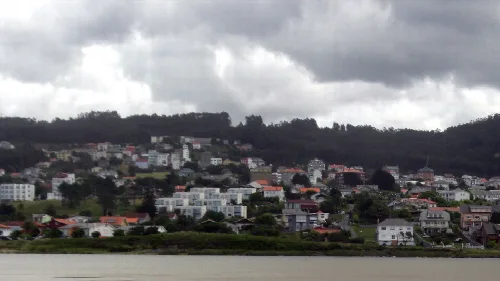 Häuser und Hügel in Valdoviño bei bewölktem Himmel.