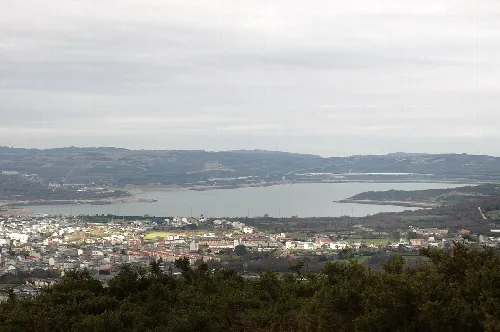 Vista panorámica de un lago y un pueblo con casas y vegetación.