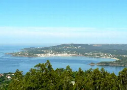 Vista de la ría de Ares con vegetación y pueblo en el horizonte.