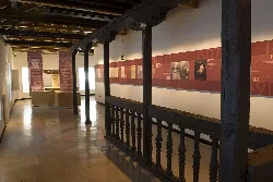 Interior de una galería con vigas de madera y paneles informativos en la pared.