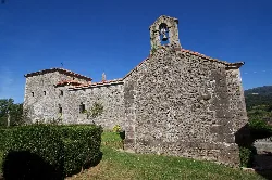 Stone building with bell tower and gardens in Colunga.