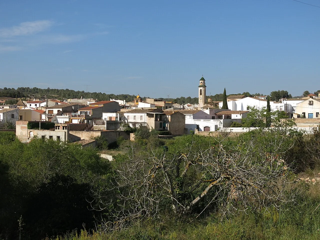 View of a town with white houses and a church with a clock.