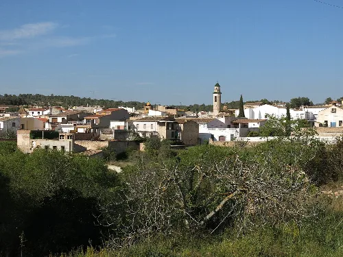 Blick auf eine Stadt mit weißen Häusern und einer Kirche mit Uhr.