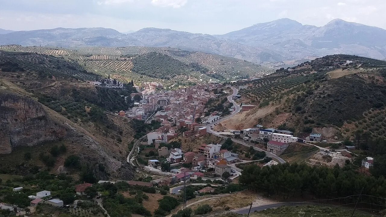 Vista de un pueblo en las colinas con montañas al fondo