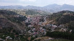 Vista de un pueblo en las colinas con montañas al fondo