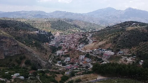 Blick auf eine Stadt in den Hügeln mit Bergen im Hintergrund