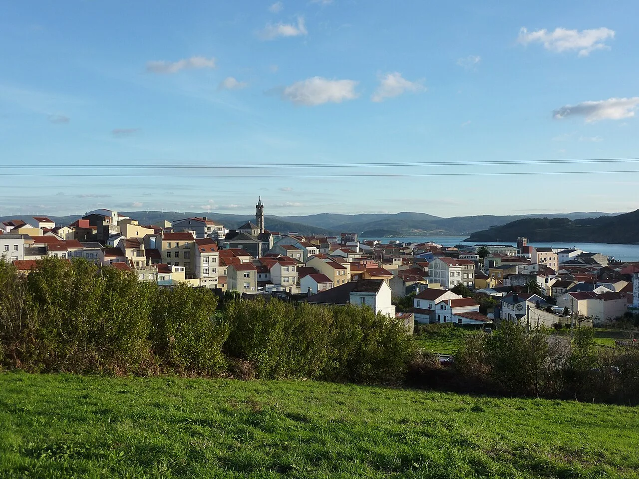 View of Cariño with houses, church, and sea in the background.