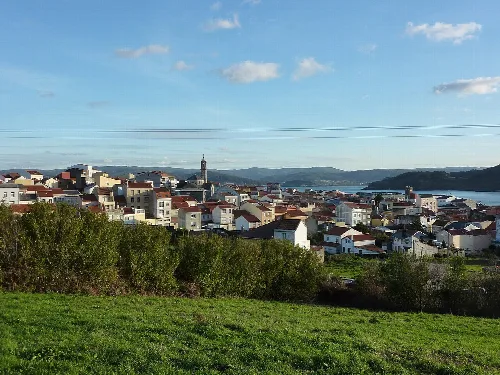 View of Cariño with houses, church, and sea in the background.