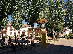 Plaza mayor con árboles, bancos y buzón de correos en La Villa de Don Fadrique.