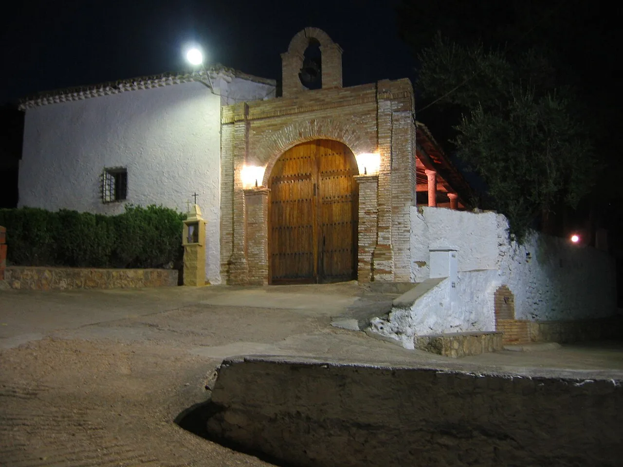 Door of the Hermitage of Piedad in Mira with brick walls and night lighting.