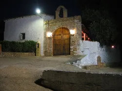 Door of the Hermitage of Piedad in Mira with brick walls and night lighting.