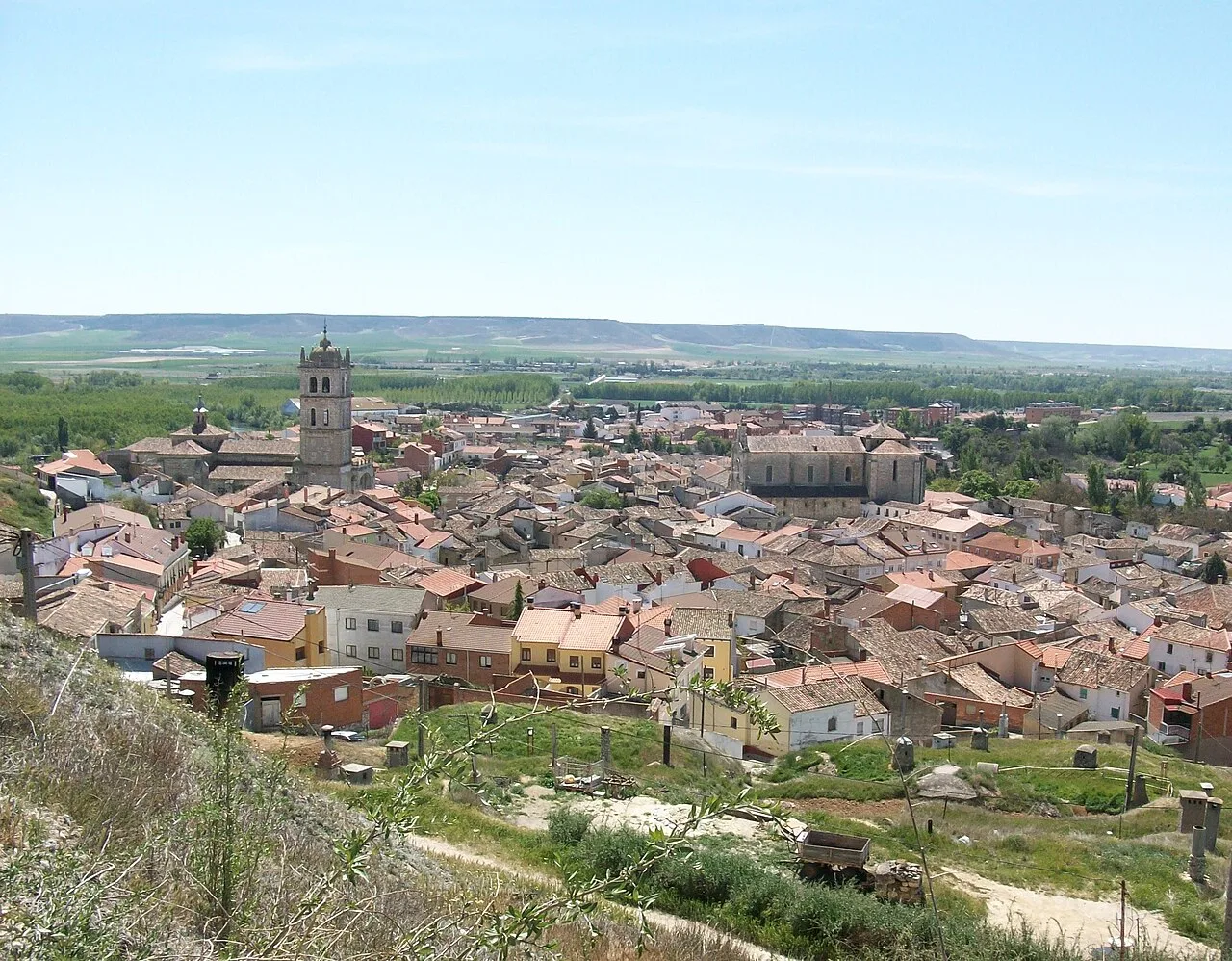 Panoramischer Blick auf Dueñas mit Kirche und ländlicher Landschaft.