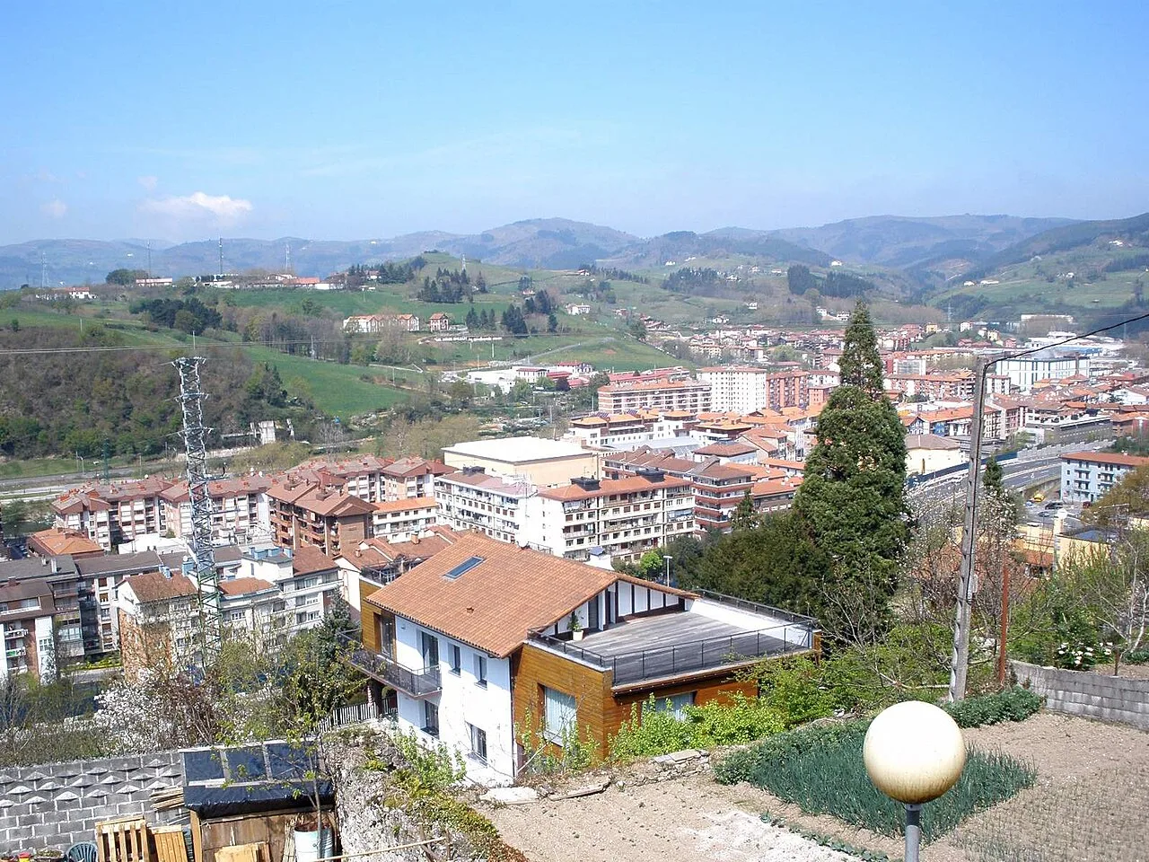 View of Villabona with houses, mountains, and blue sky.