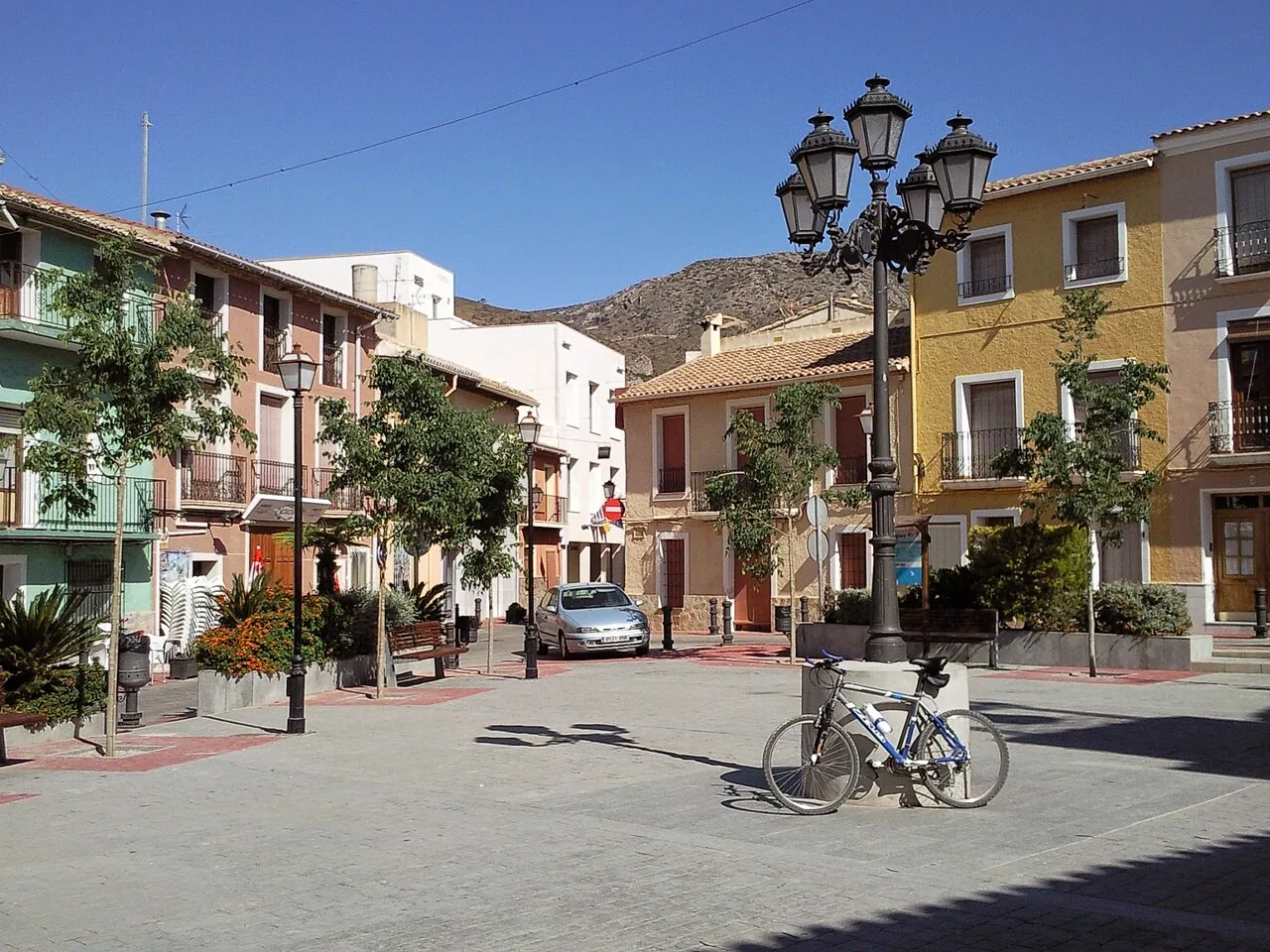 Plaza con farola, bicicleta y edificios en Aguas de Busot.