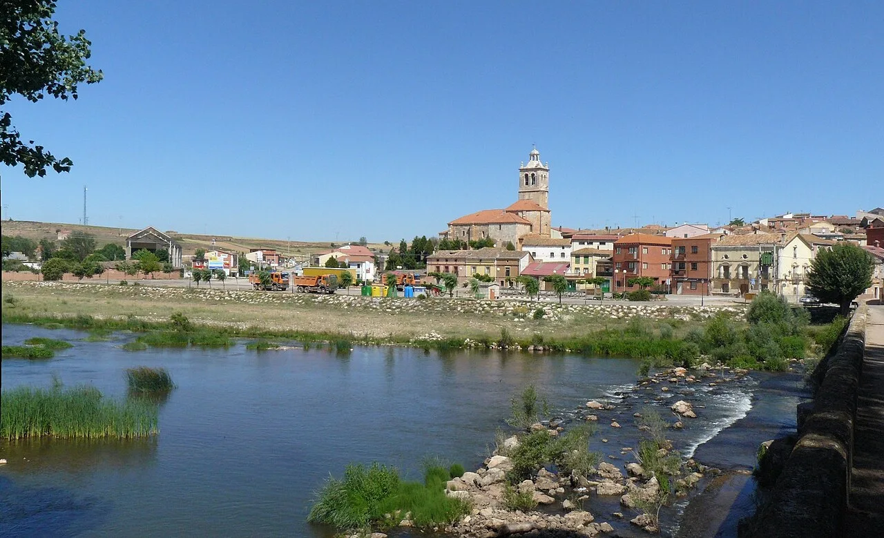 Blick auf den Fluss und die Stadt Tordómar mit der Kirche im Hintergrund.