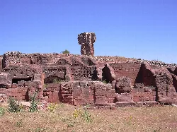 Ruinas de piedra y torre en un yacimiento arqueológico.