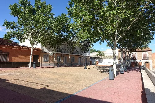 Plaza de España con árboles y edificios en Albarreal de Tajo.