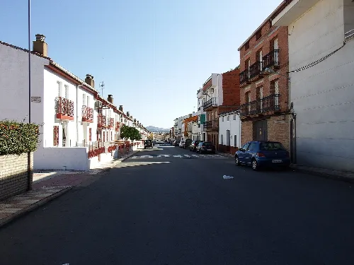 Calle en Agudo con casas blancas y coches estacionados.