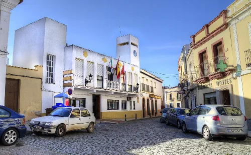 Rathaus in La Zarza mit Flaggen und geparkten Autos.