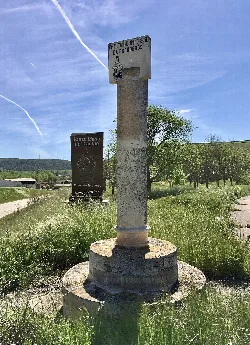 Säulen und Schilder in einer ländlichen Landschaft mit Bäumen und Feldern.