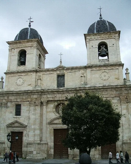 Facade of the church with two towers and a tree in front.