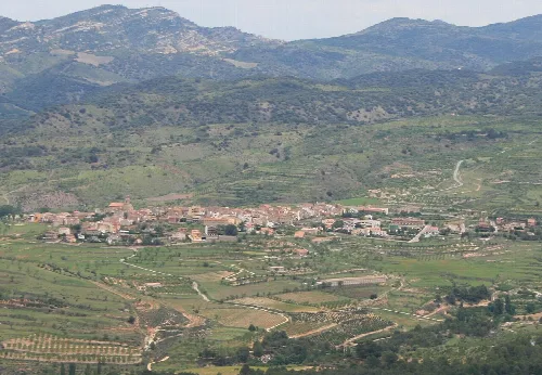 Landschaft mit Dorf, Bergen und grünen Feldern
