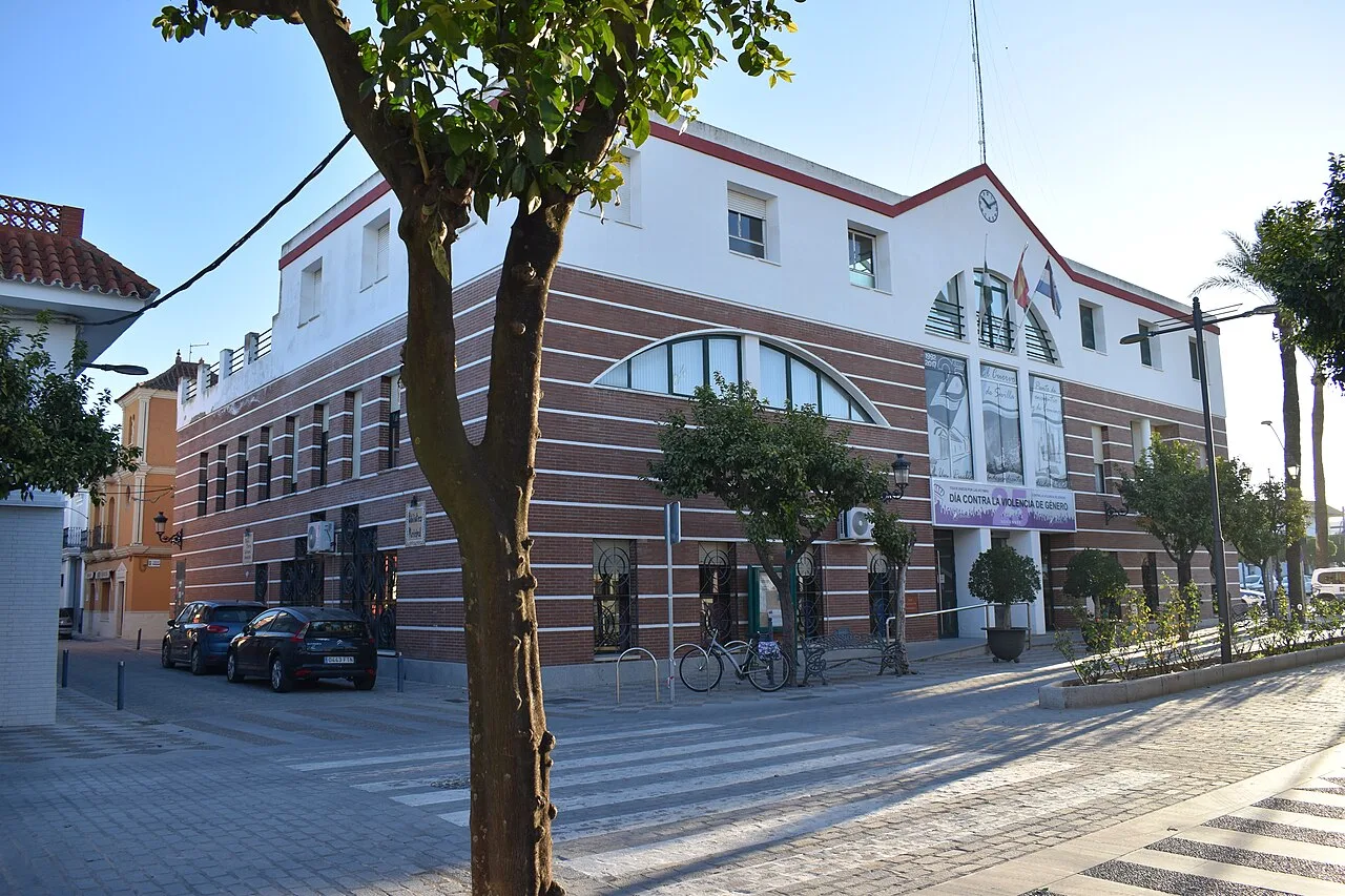 Edificio blanco con fachada moderna y árboles en la calle en El Cuervo de Sevilla.