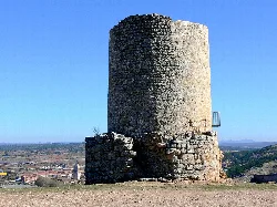 Round stone tower on open landscape with blue sky.