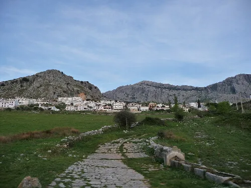 Steinweg im Vordergrund mit Ort und Bergen im Hintergrund.