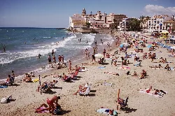 Strand mit Menschen auf Sand und im Wasser in Sitges.