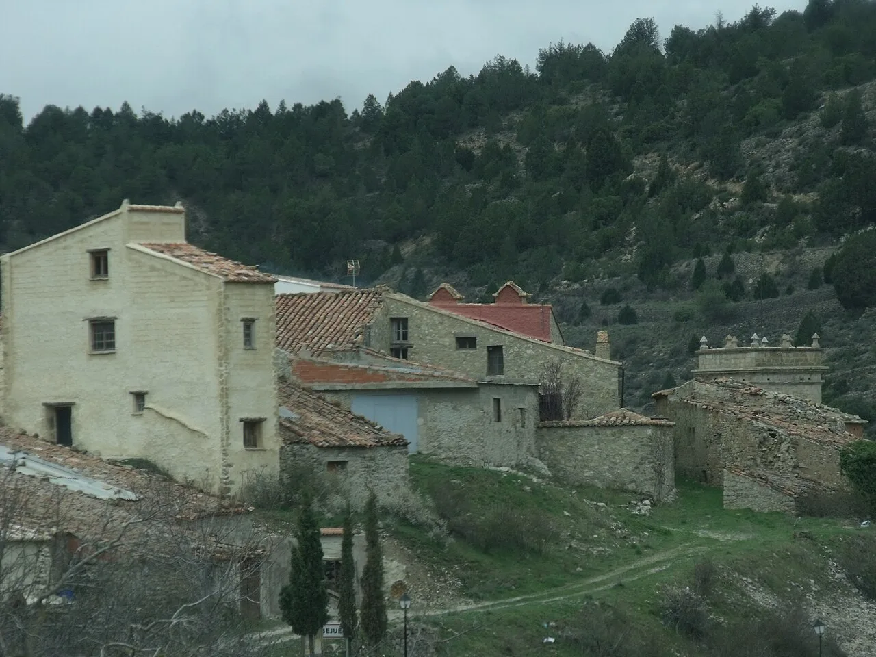 Casas de piedra con tejados de teja en Abejuela, rodeadas de montañas.