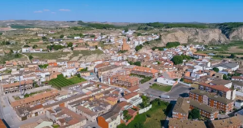 Aerial view of a town with buildings and streets in a landscape of hills and fields.