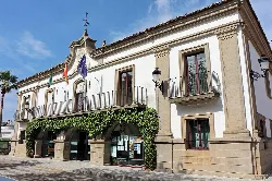 Town hall building with flags and greenery on the facade.