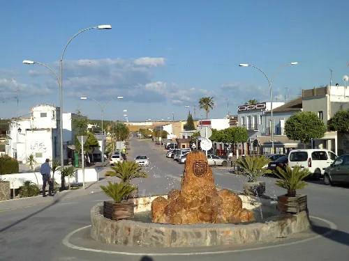 Steinbrunnen in El Palmar de Troya mit Pflanzen und Straßen drumherum.