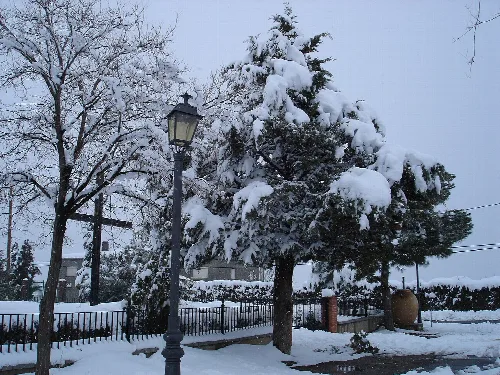 Schneebedeckte Bäume und Laternen in einer Winterlandschaft in Polícar.