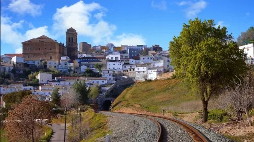 Eisenbahnlinien im Vordergrund und Stadt mit Kirche auf Hügel im Hintergrund.