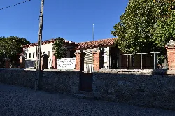Schulgebäude in Torregamones mit Steinmauer und Metallzaun.