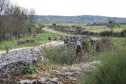Puente romano de piedra con arcos en un paisaje rural