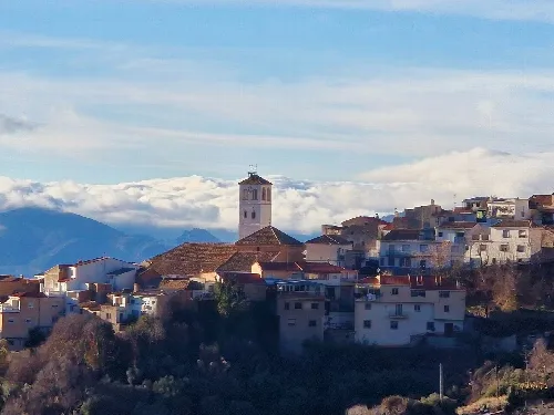 Weiße Häuser und ein Turm in Cogollos Vega mit Bergen im Hintergrund