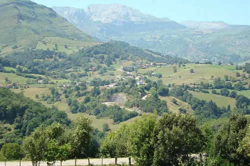 Paisaje de valle con casas, árboles y montañas en Cantabria