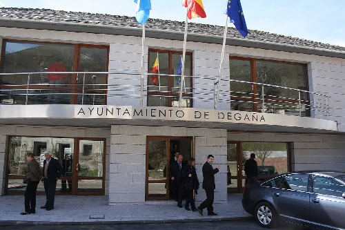 Edificio moderno con banderas y varias personas en la entrada.