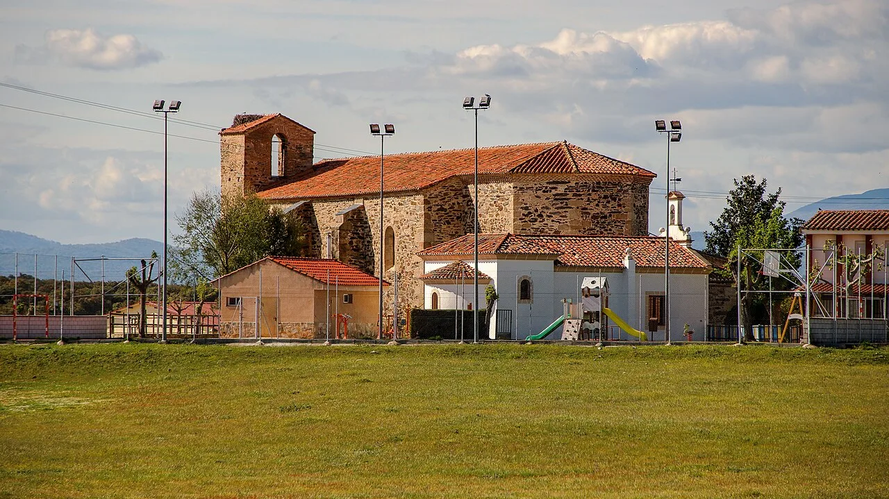 Stone building with bell tower next to a playground and open field.