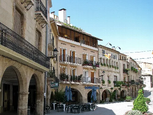 Hauptplatz mit Gebäuden und Cafés im Freien mit Tischen und Sonnenschirmen in Les Borges Blanques.