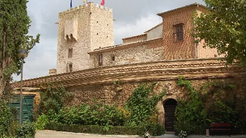 Castillo de Cortes con murallas y torre en un día nublado.