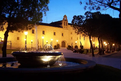 Edificio histórico con fuente en la plaza, iluminado por la noche en Torrijos.