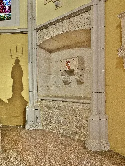 Interior de la capilla con un monumento funerario y una inscripción en piedra.