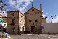 Fachada de un convento con muro de piedra y cruz en Tarancón.