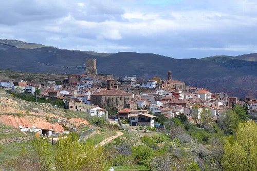 Vista panorámica de un pueblo con colinas y vegetación en el fondo.