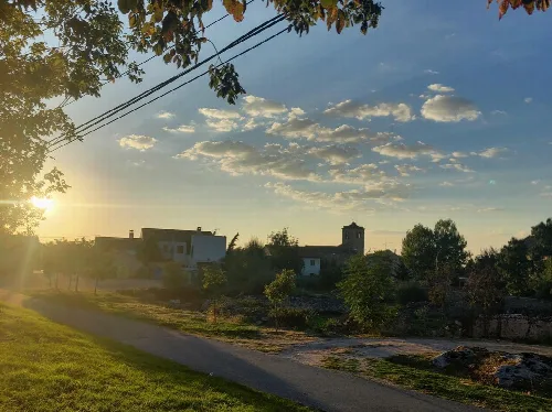 Landscape of La Losa with houses, trees, and a sky with scattered clouds at sunset.